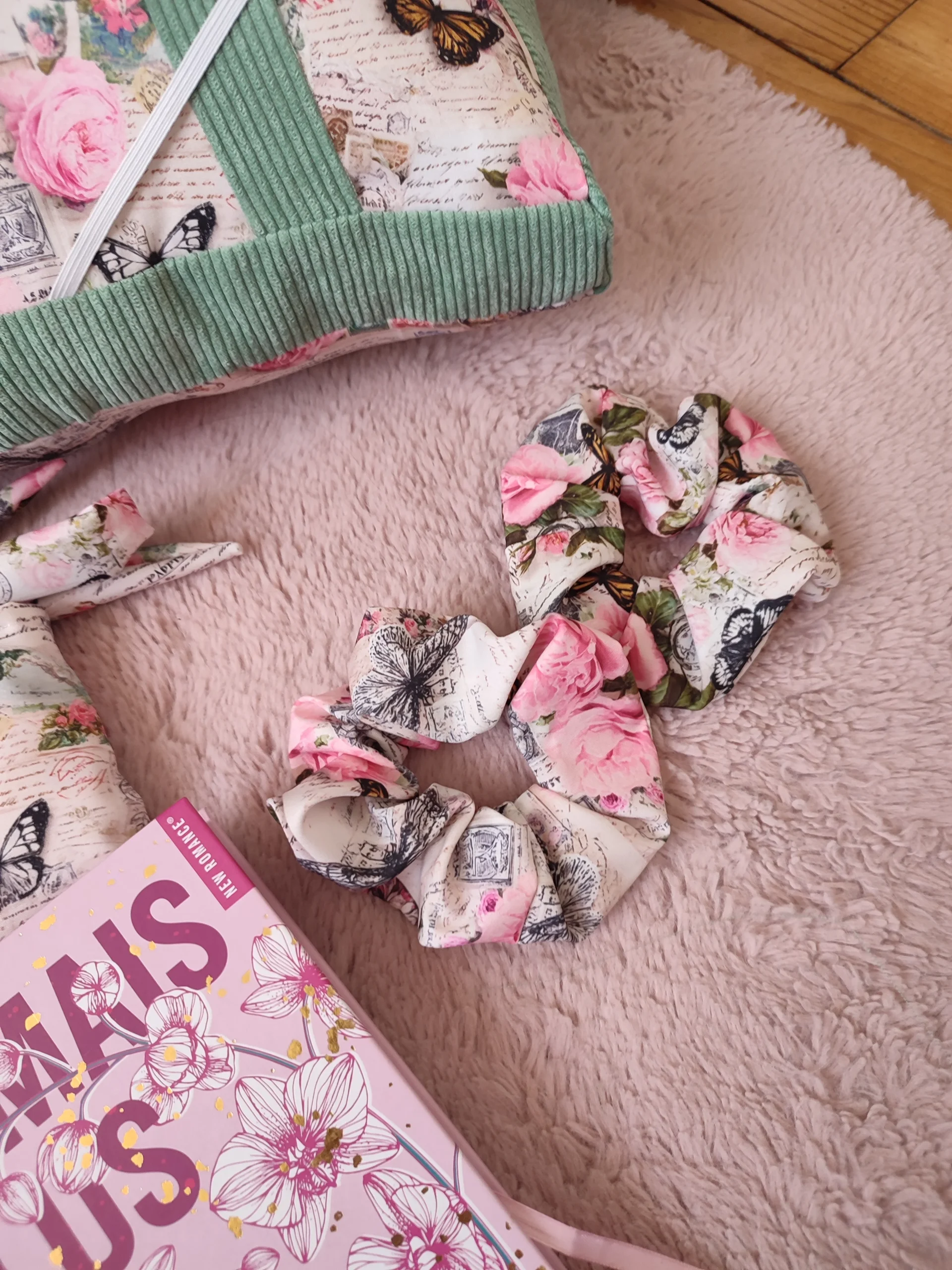 Deux chouchous avec des motifs de papillons et de fleurs sur un tapis couleur rose clair