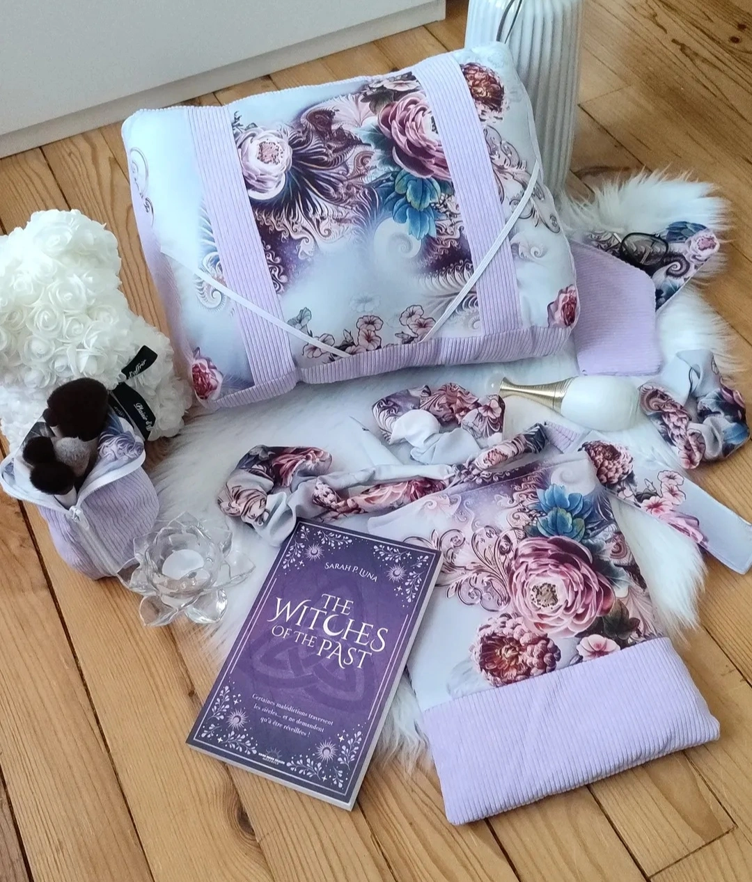Ensemble-cêtelé-mauve-et-tissu-Dahlia ensemble comprenant un coussin de lecture, des chouchous, un étui à lunette, une pochette à livre, une trousse et un marque page réalisés avec un tissu à motif fleur de Dahlia et un tissu côtelé mauve accompagné d'un ours fait en fausse fleur blanche, d'un parfum de couleur blanc et or et d'une fleur de nénuphar en verre