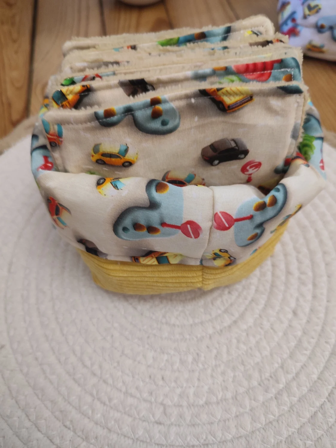 panier et lingettes tissus Mini Drive de couleur beige avec motif de voiture et de route et un tissu côtelé jaune sur un tapis beige