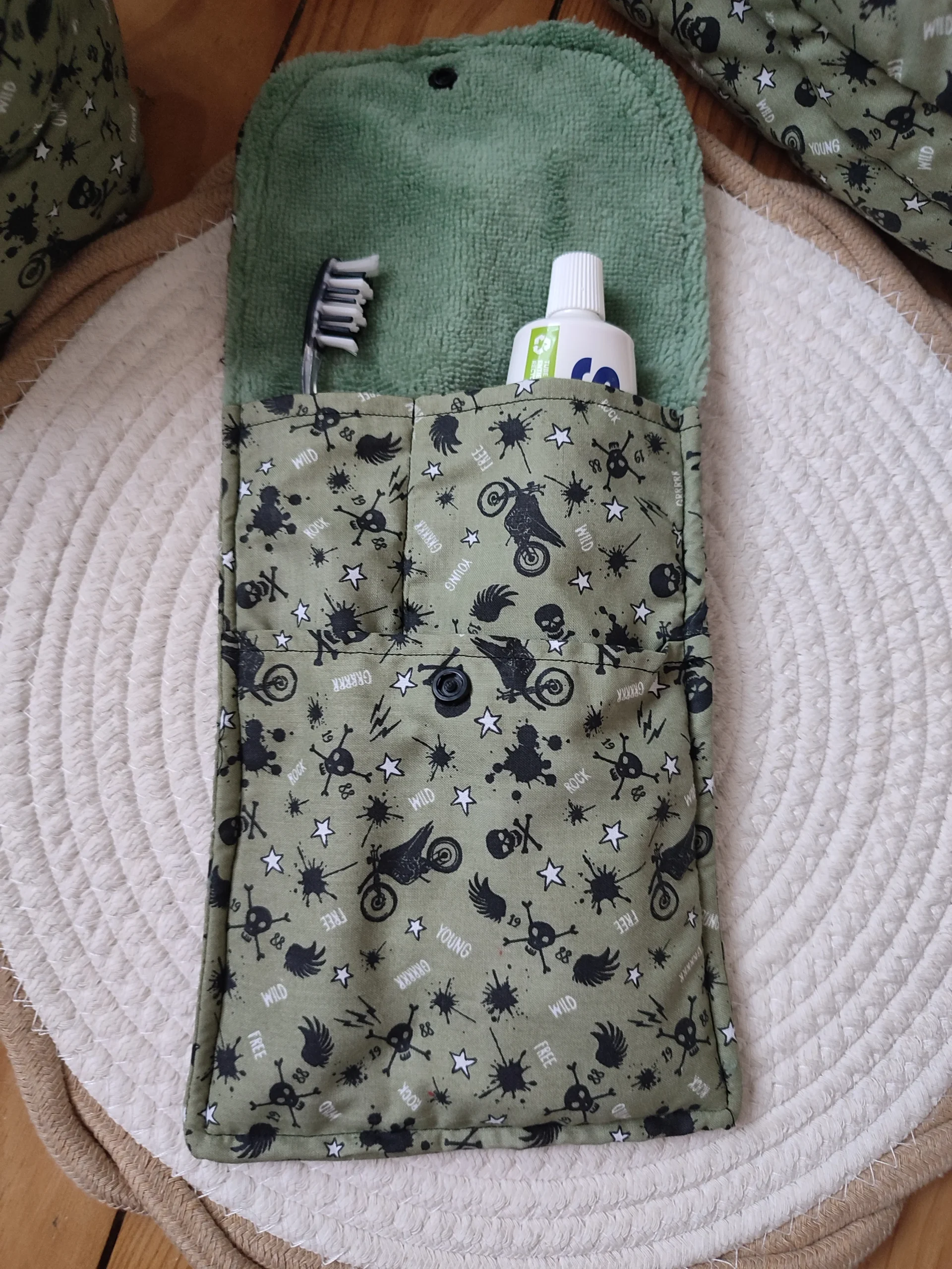 Pochette avec brosse à dent et dentifrice ouverte de couleur kaki avec des motifs moto et tête de mort de couleur noir