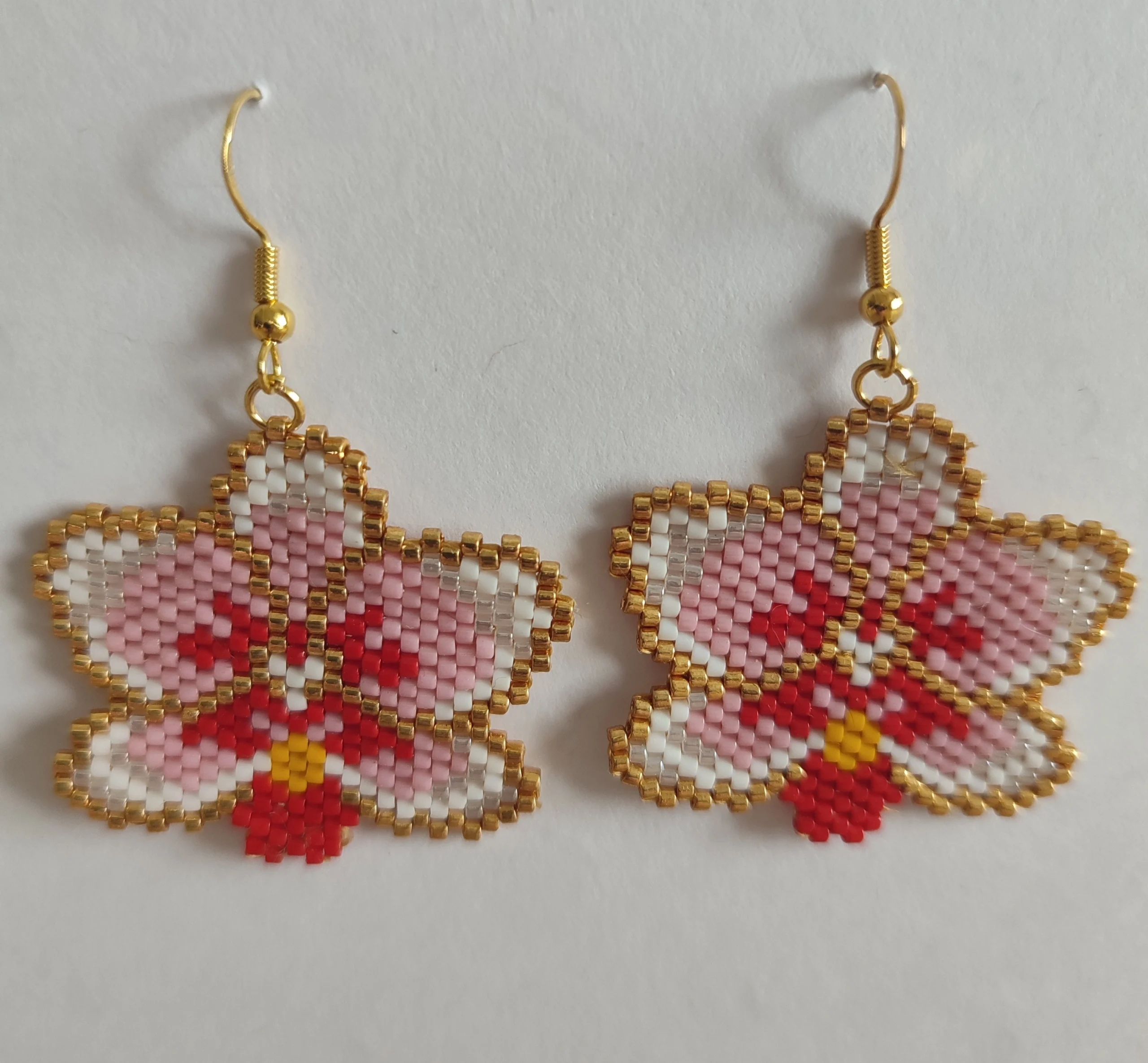 boucle d'oreille fleur orchidée paire de boucle d'oreille en forme d'orchidée fait en tissage de perle miyuki de couleur rose, rouge et or sur un fond blanc