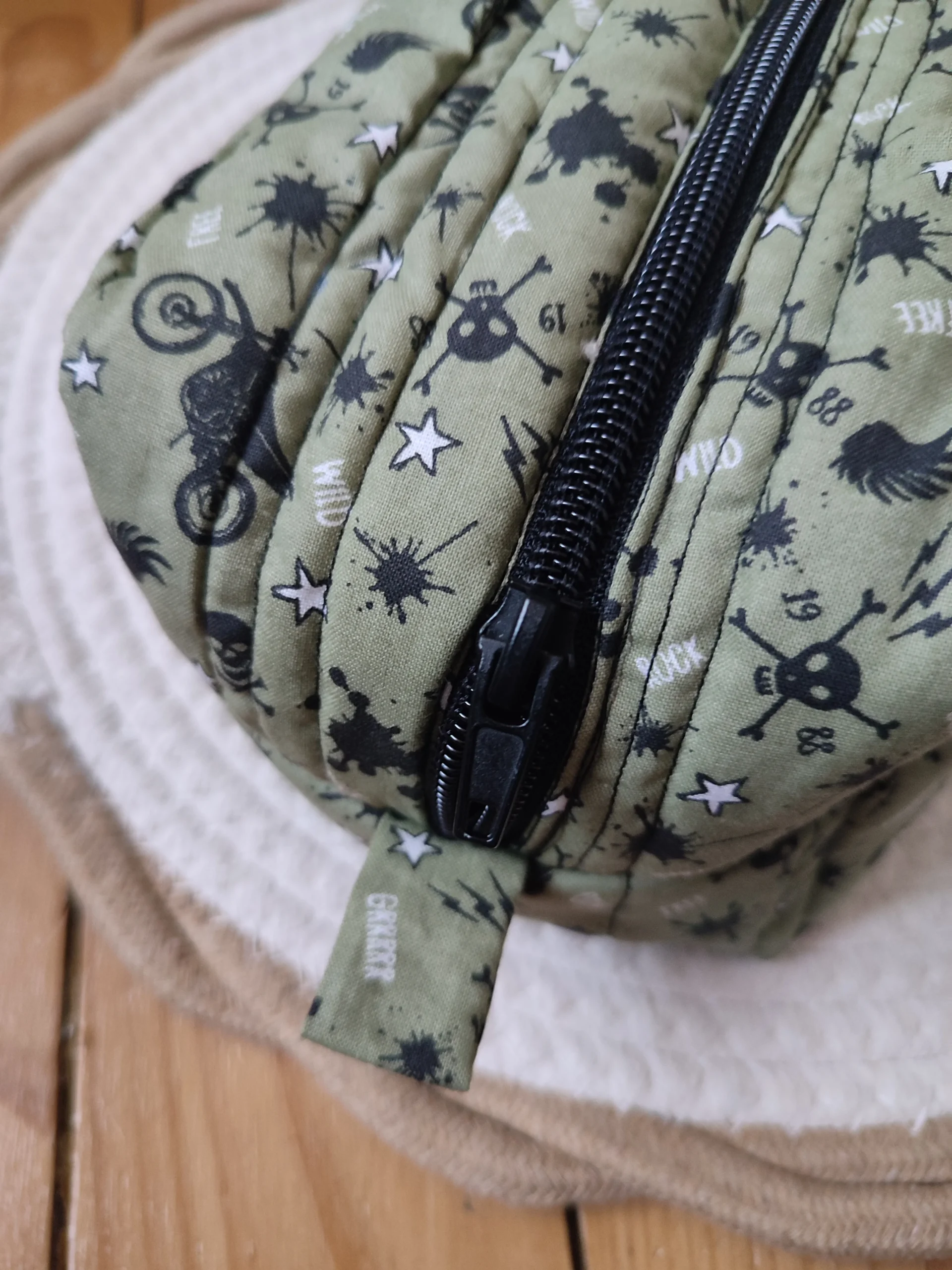 fermeture éclair noire d'une trousse de toilette kaki avec motif moto et tête de mort noir