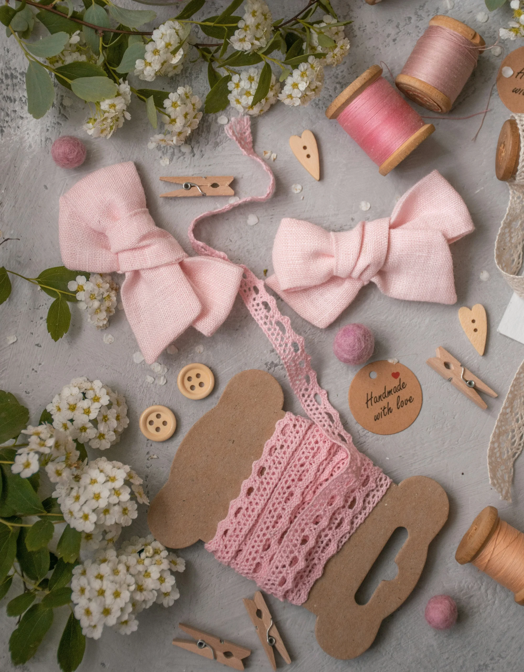 ensemble de 3 bobines de fils rose, violet clair et beige, 2 noeuds rose, de la dentelle rose, des boutons et des épingles en bois
