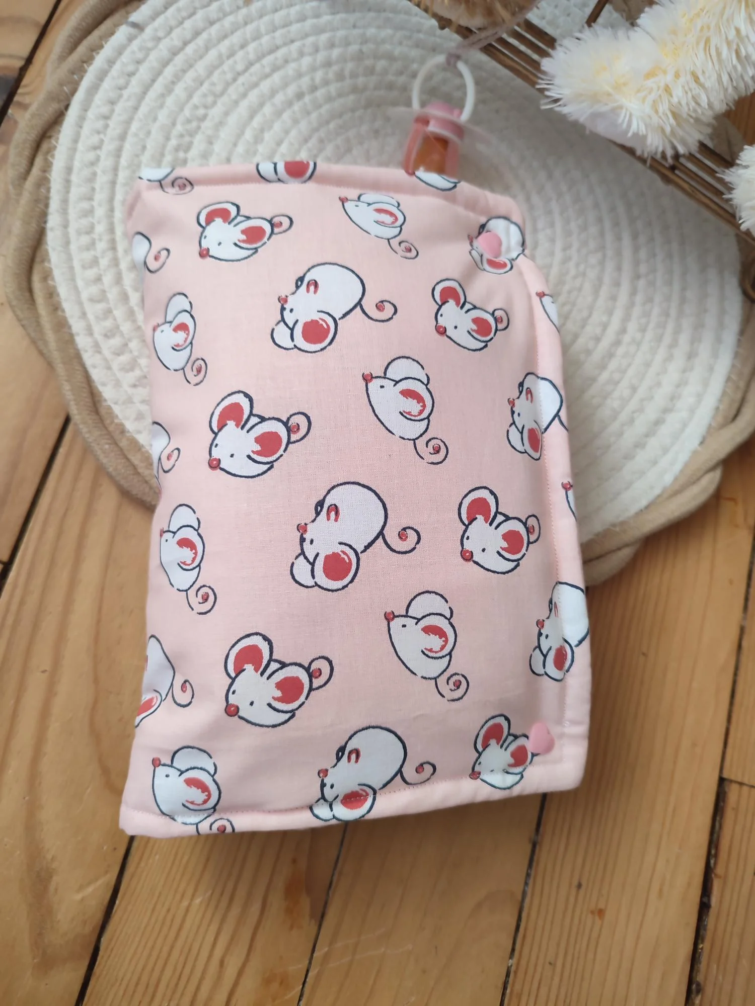 pochette à lange fait main fermée, elle est de couleur rose claire avec des motifs de souris blanche