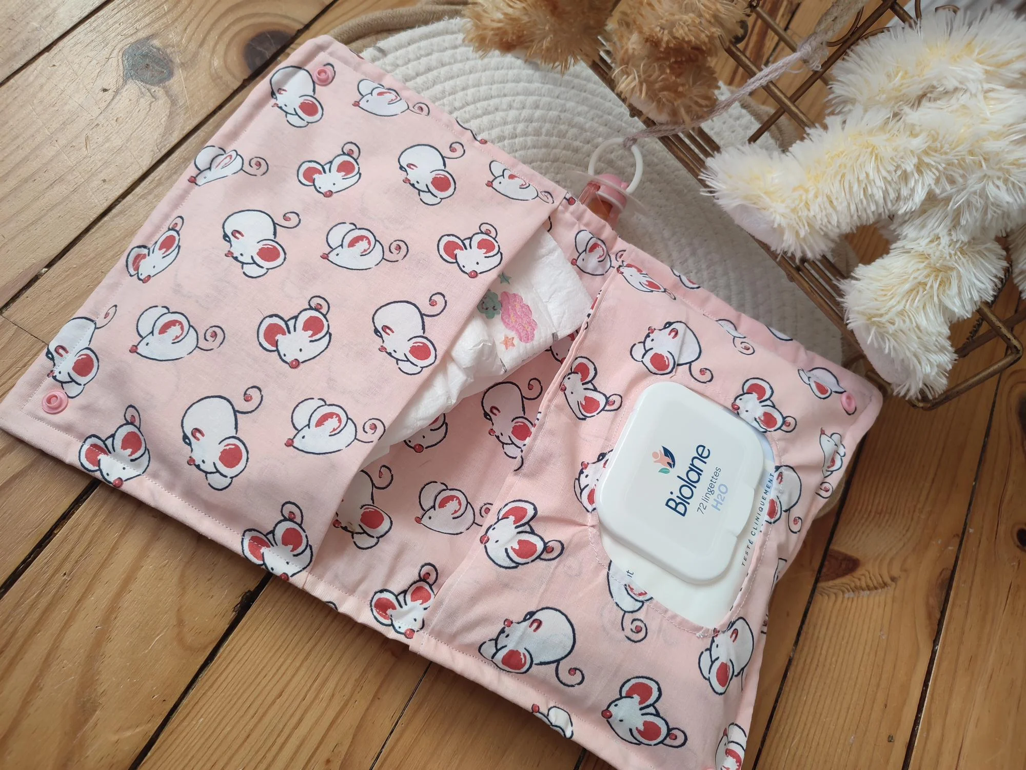 pochette à lange fait main ouverte, elle est de couleur rose claire avec des motifs de souris blanche