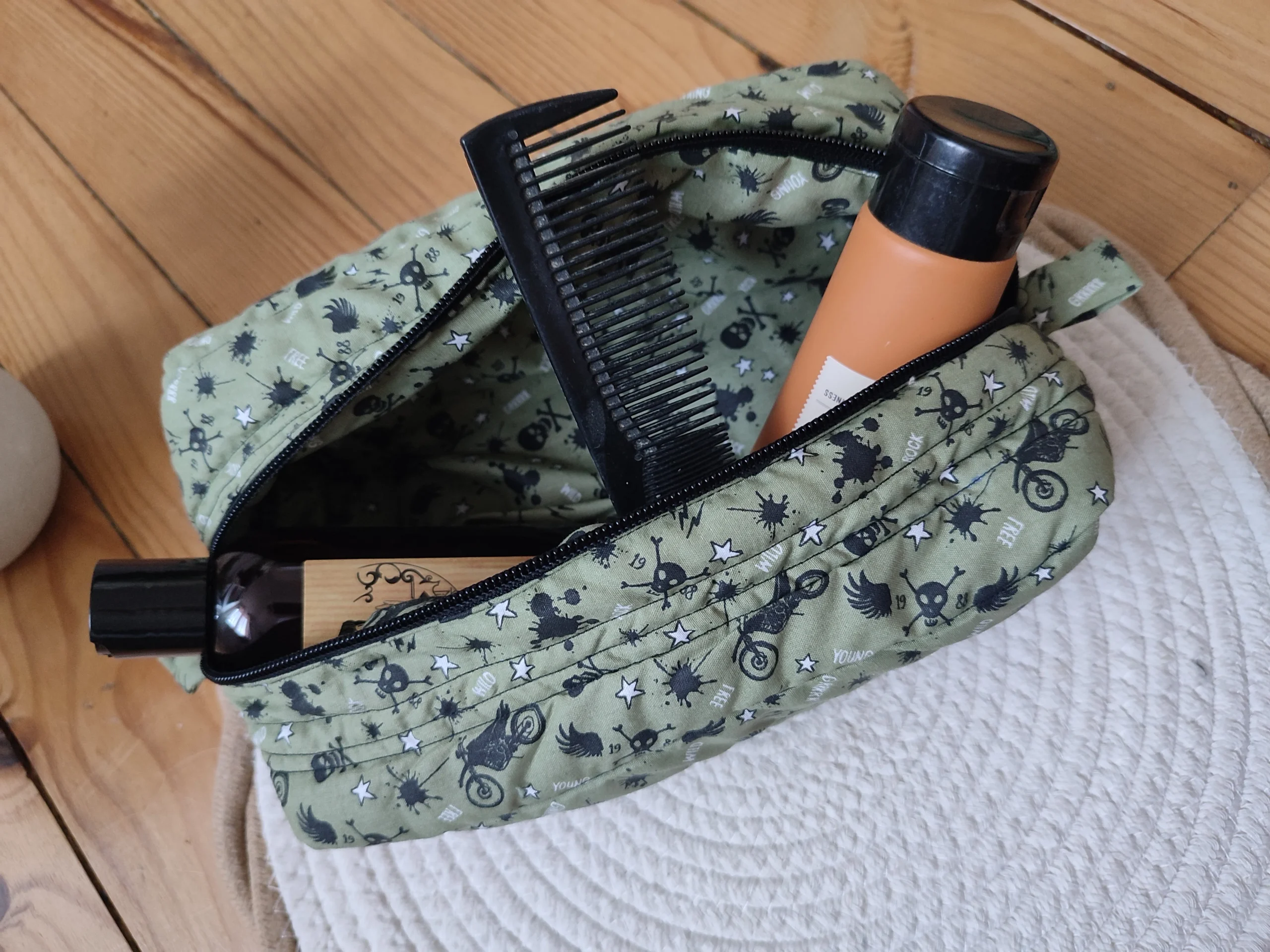 trousse de toilette kaki avec motif moto et tête de mort noir ouverte avec un peigne et deux flacon de produit pour la toilette à l'intérieur
