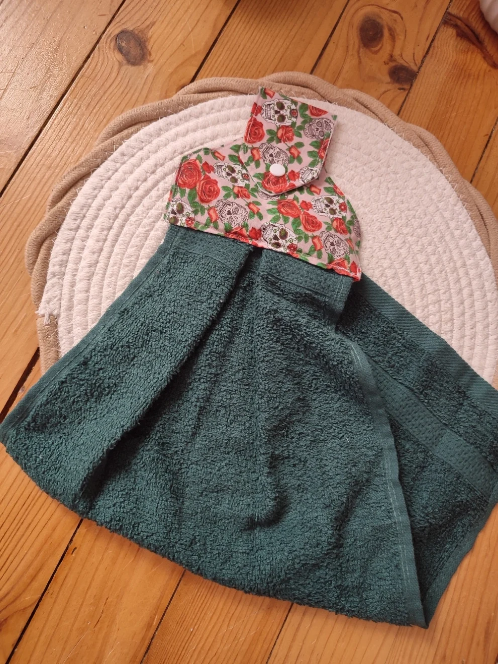 vu d'un essui main de couleur rose clair et avec motif tête de mort avec des rose rouge et de sa serviette de couleur verte foncée pliée en deux