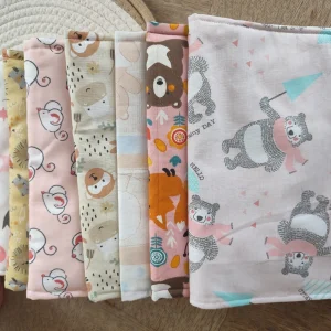 lot de pochette à lange artisanale nomades des différents thèmes superposés sur un tapis beige