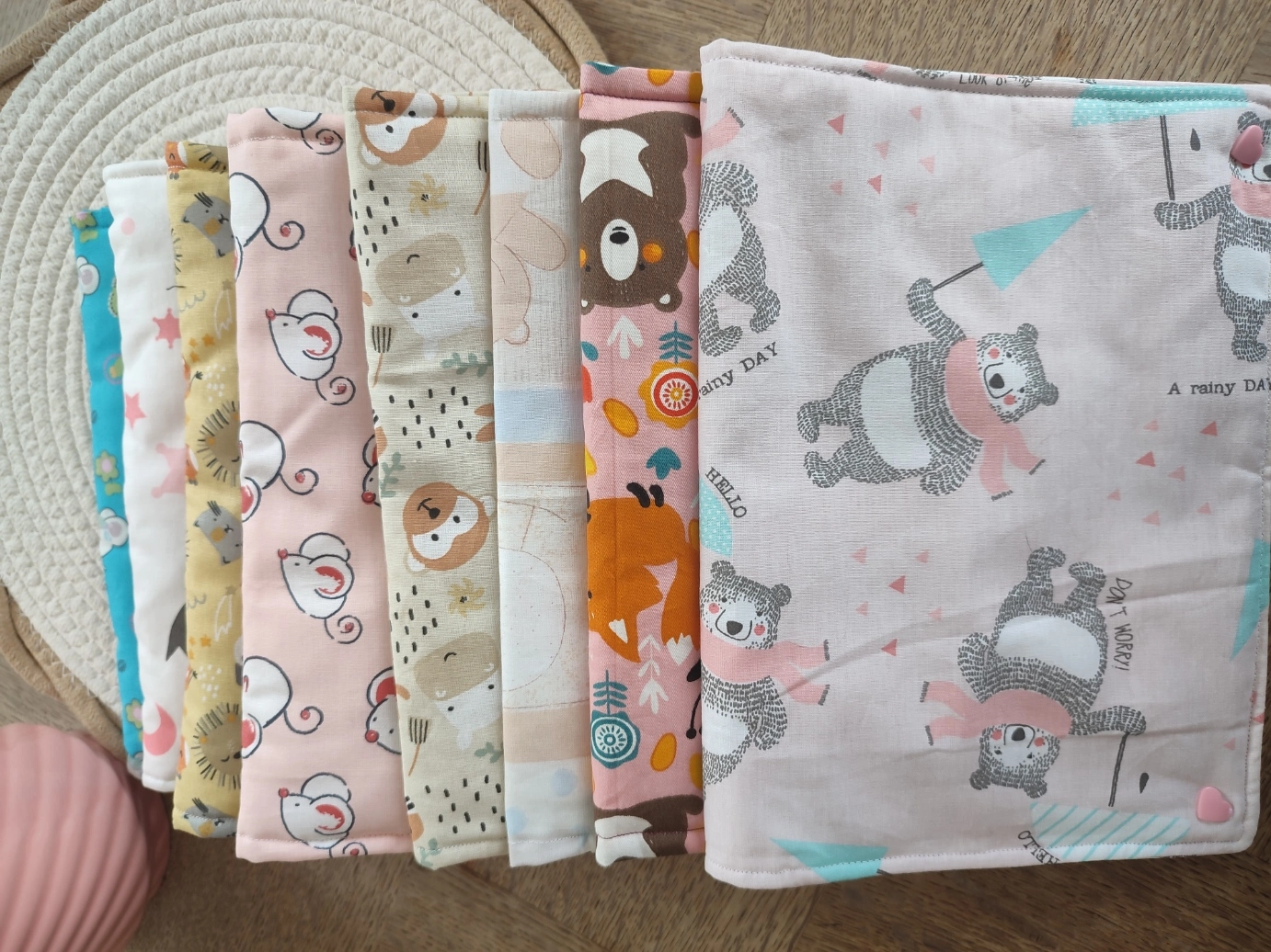 lot de pochette à lange artisanale nomades des différents thèmes superposés sur un tapis beige