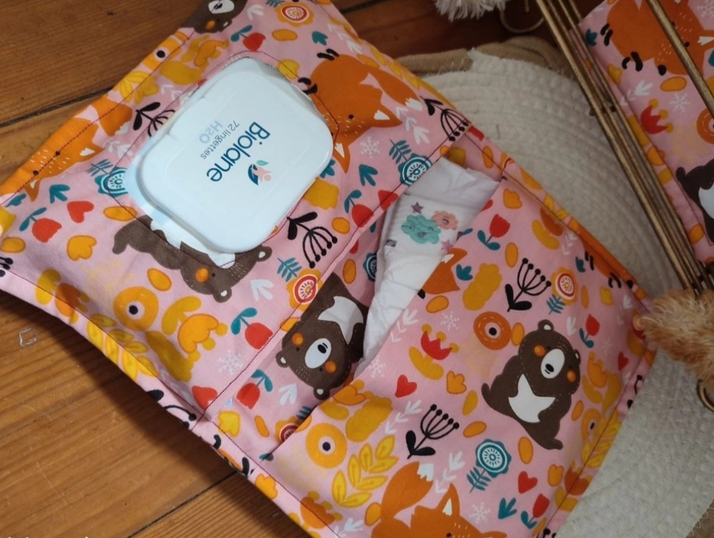 pochette à lange artisanale ouverte, elle est de couleur rose claire avec des motifs d'ours et de renard