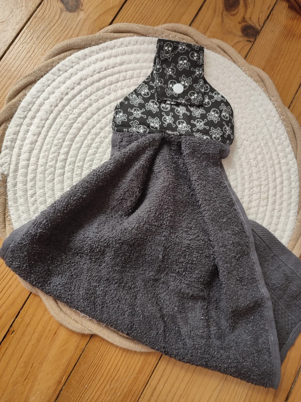 vu d'un essui main de couleur noir et avec motif tête de mort et de sa serviette de couleur gris anthracite pliée en deux