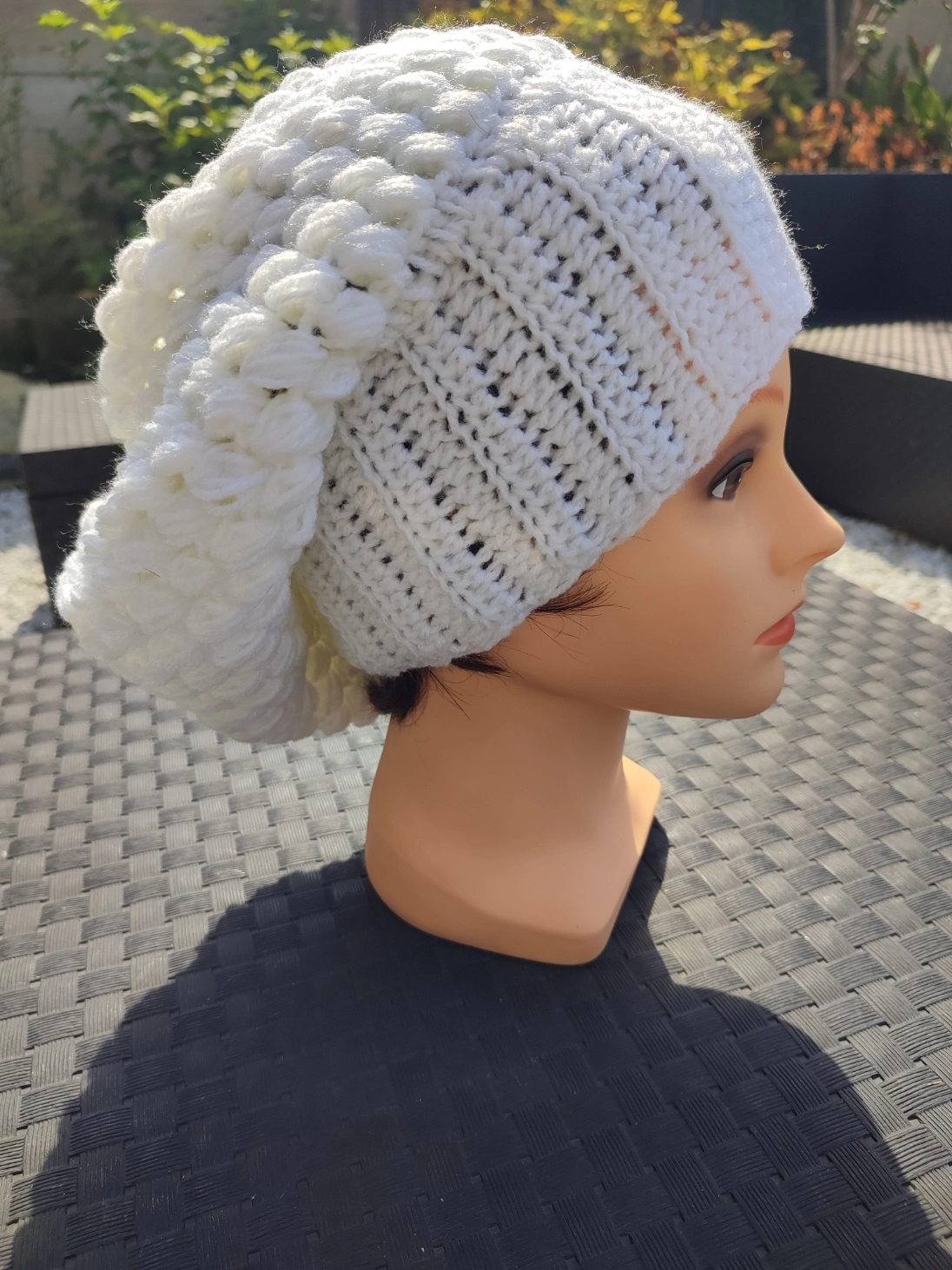 bonnet retombant fait main en crochet de couleur blanc cassé sur une tête de mannequin