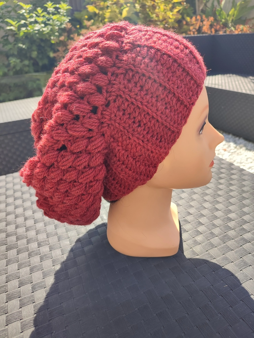 bonnet retombant fait main en crochet de couleur bordeau sur une tête de mannequin