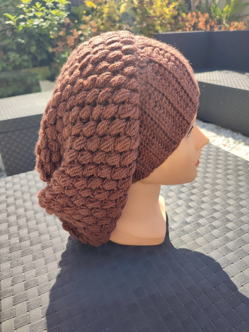 bonnet retombant fait main en crochet de couleur marron sur une tête de mannequin