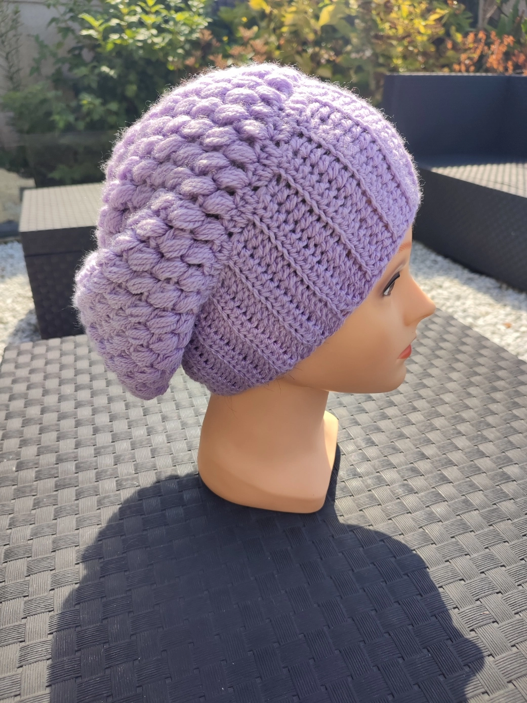 bonnet retombant fait main en crochet de couleur mauve sur une tête de mannequin