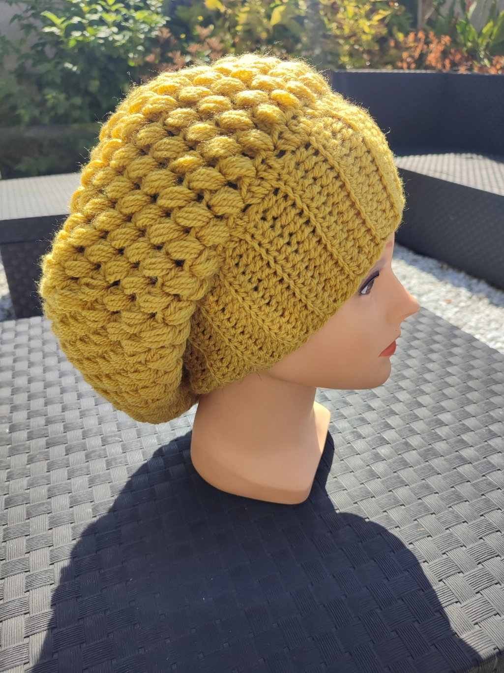 bonnet retombant fait main en crochet de couleur moutarde sur une tête de mannequin