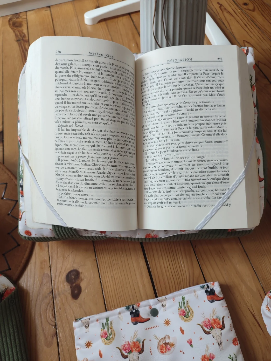 Coussin de lecture Fleurs de l'ouest fait main avec un tissus côtelé de couleur vert et un tissus avec des cactus, des bottes de cowboys, des chapeaux de cowboys et des tête de buffle tête de mort sur fond blanc avec un livre ouvert