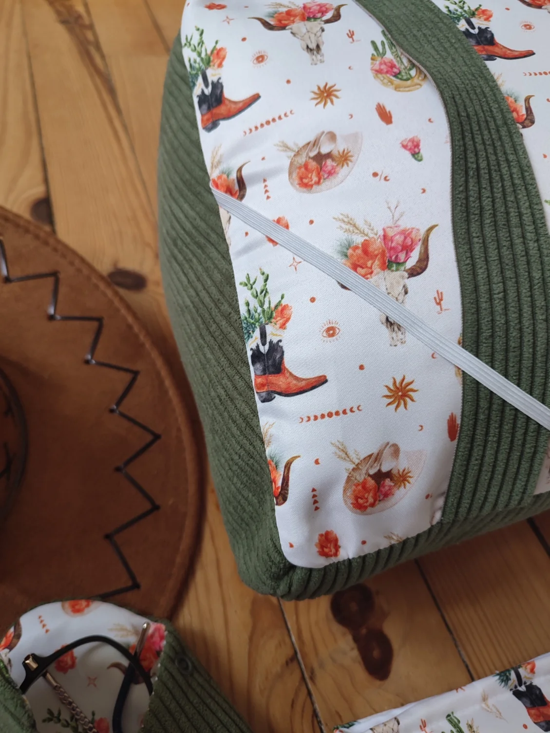 Coussin de lecture Fleurs de l'ouest fait main avec un tissus côtelé de couleur vert et un tissus avec des cactus, des bottes de cowboys, des chapeaux de cowboys et des tête de buffle tête de mort sur fond blanc vu de côté