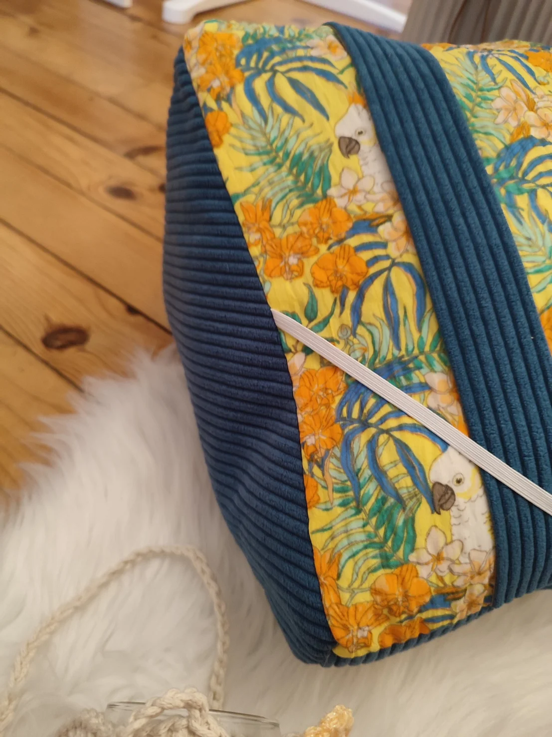 Coussin de lecture Lagon bleu fait main avec un tissu côtelé colvert et un tissu avec des motifs de cacatoès et de fleurs tropical sur fond jaune vue de côté