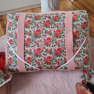 Coussin de lecture Rose de l'ombre fait main avec un tissu côtelé vieux rose et un tissu avec des motifs de tête de mort et de rose sur fond rose vue de haut