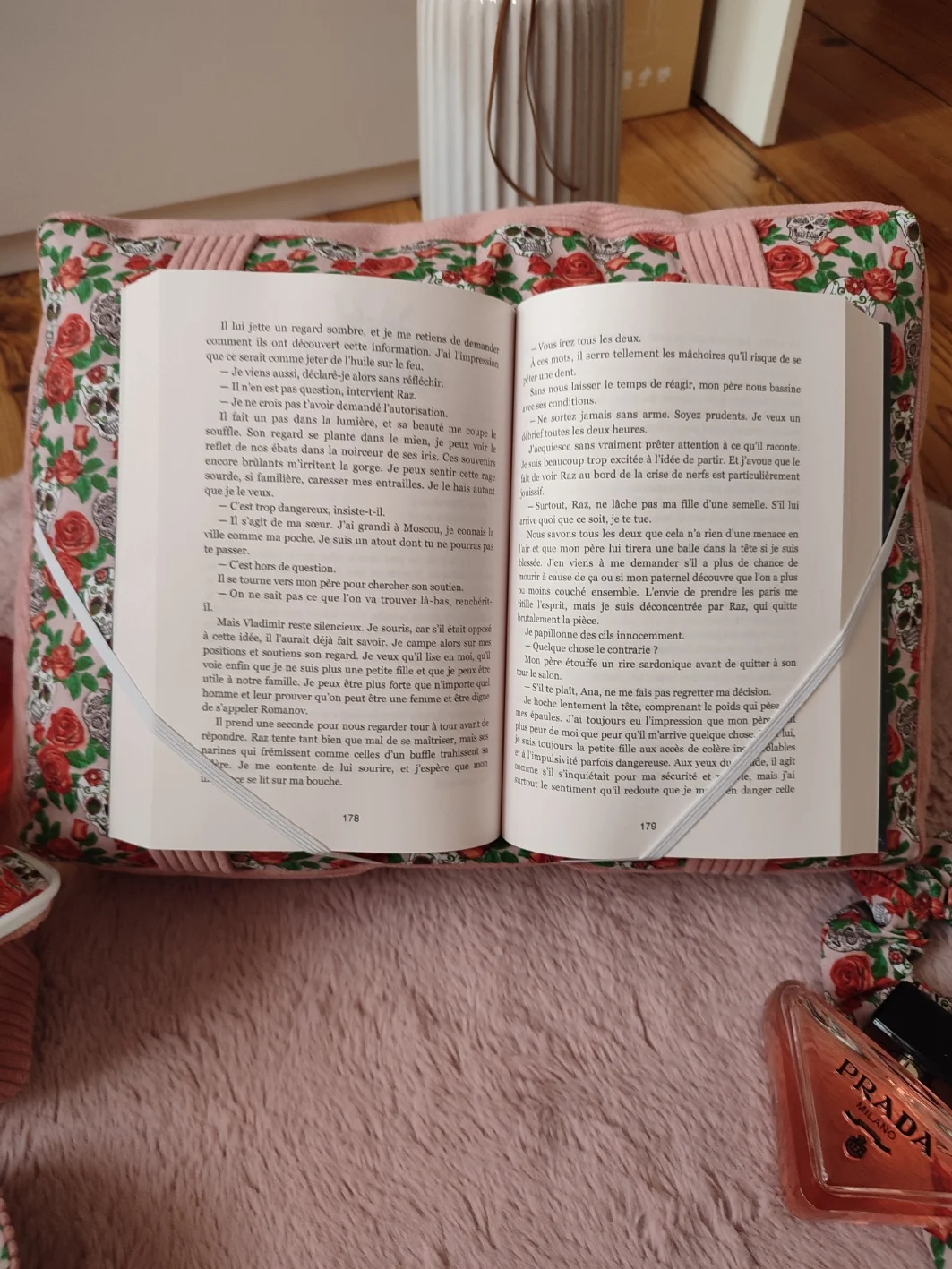 Coussin de lecture Rose de l'ombre fait main avec un tissu côtelé vieux rose et un tissu avec des motifs de tête de mort et de rose sur fond rose avec un livre ouvert