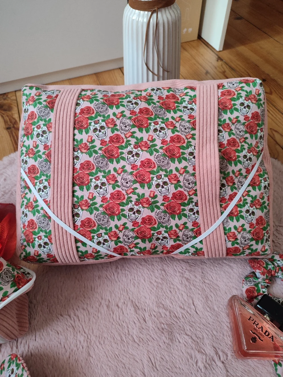 Coussin de lecture Rose de l'ombre fait main avec un tissu côtelé vieux rose et un tissu avec des motifs de tête de mort et de rose sur fond rose vue de haut