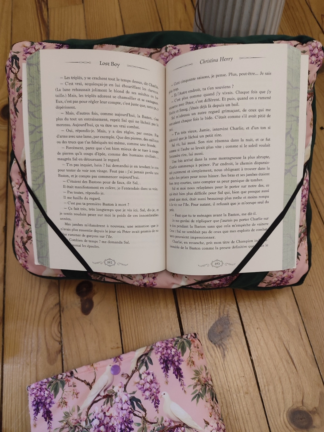 Coussin de lecture Sous les glycines fait main avec un tissus velours de couleur vert foncé et un tissus avec des fleurs de glycines et des colombes sur fond rose avec un livre ouvert