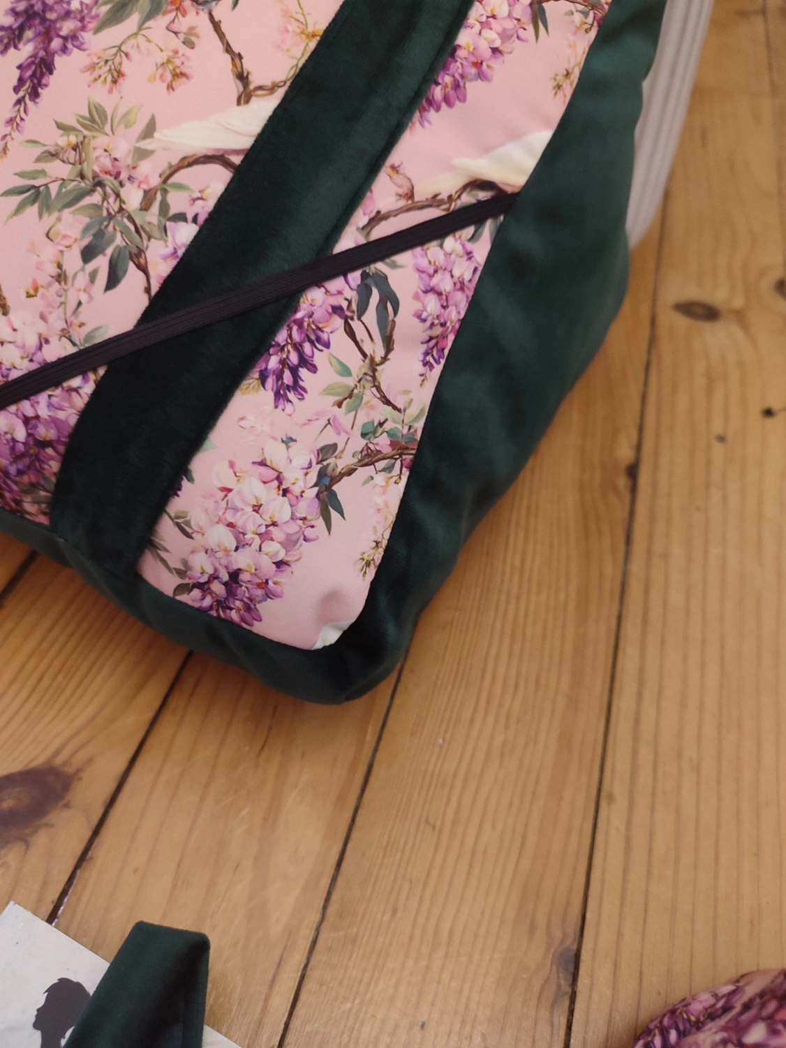 Coussin de lecture Sous les glycines fait main avec un tissus velours de couleur vert foncé et un tissus avec des fleurs de glycines et des colombes sur fond rose vu sur le côté