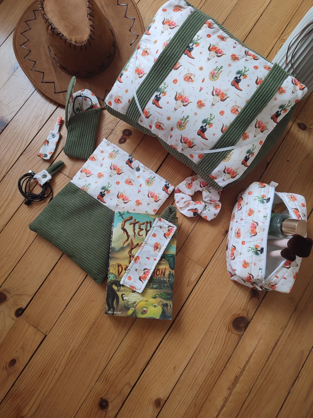 Ensemble de lecture Fleurs de l'ouest fait main avec un tissus côtelé de couleur vert et un tissus avec des cactus, des bottes de cowboys, des chapeaux de cowboys et des tête de buffle tête de mort sur fond blanc comprenant le coussin de lecture, la pochette à livre, la trousse e toilette, le chouchou, le marque page , l'étui à lunette et deux serre-câble