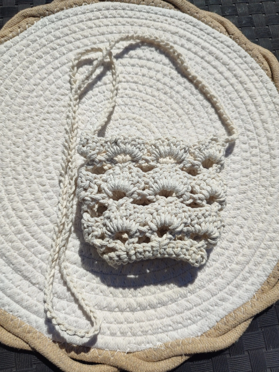Porte verre en crochet de couleur beige à plat sur un tapis