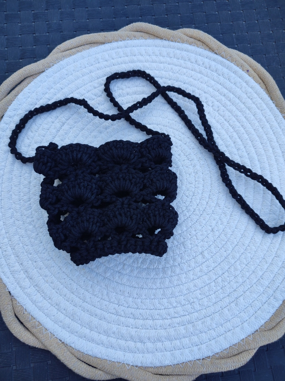 Porte verre en crochet de couleur noir à plat sur un tapis