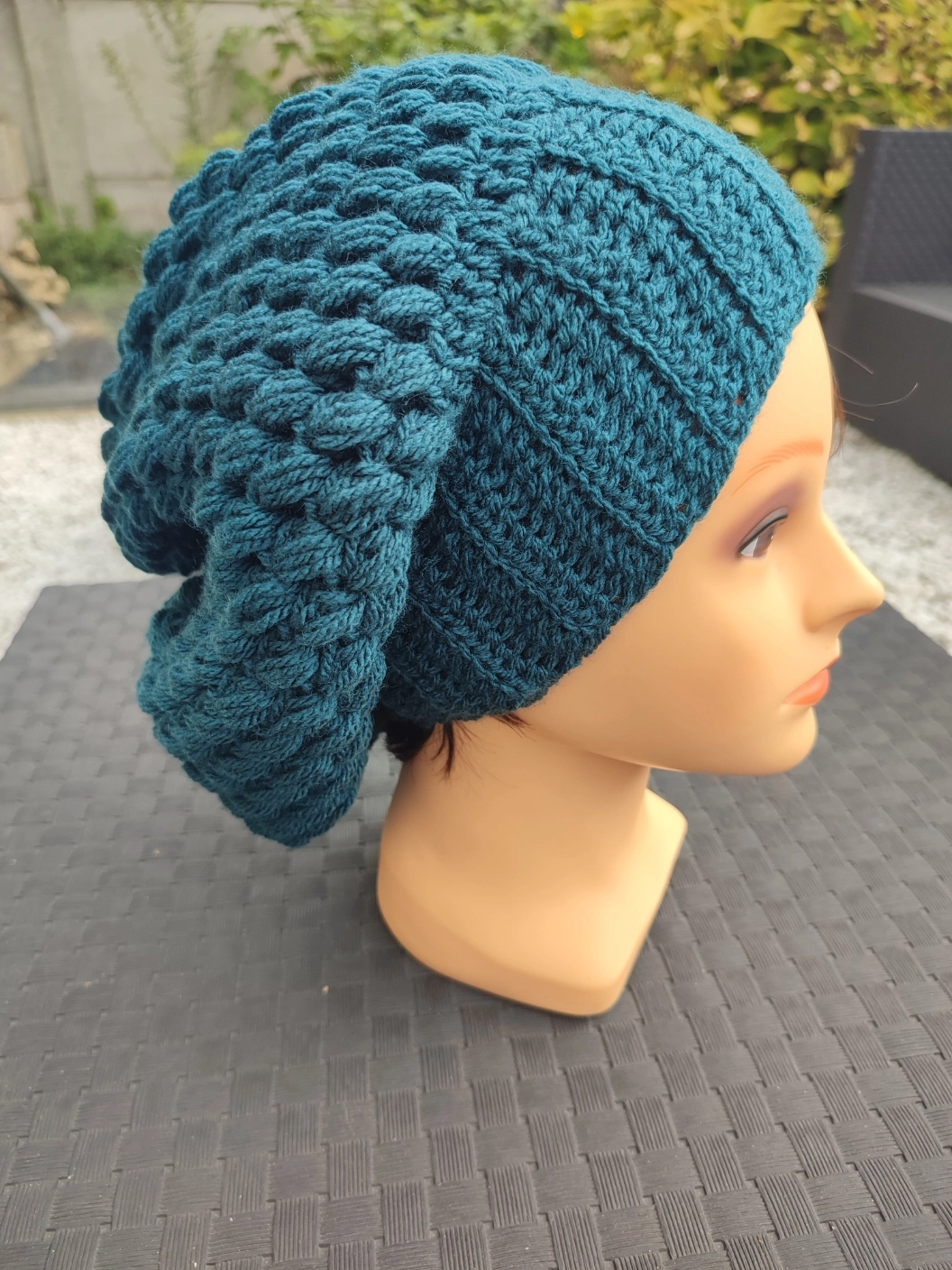 bonnet retombant fait main en crochet de couleur colvert sur une tête de mannequin