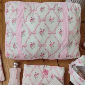 Coussin de lecture ruban rose fait main avec un tissus représentant des noeuds rose et des rose fushia sur fond bland et un tissus côtelé rose