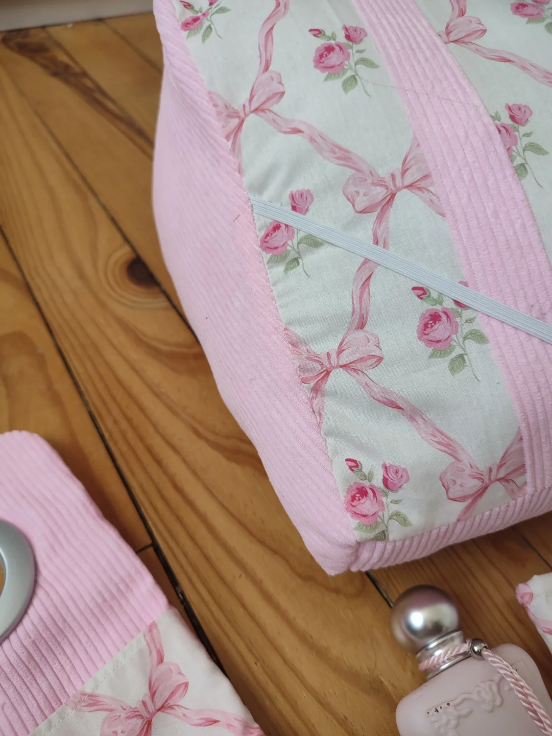 Coussin de lecture ruban rose fait main avec un tissus représentant des noeuds rose et des rose fushia sur fond bland et un tissus côtelé rose vue de côté