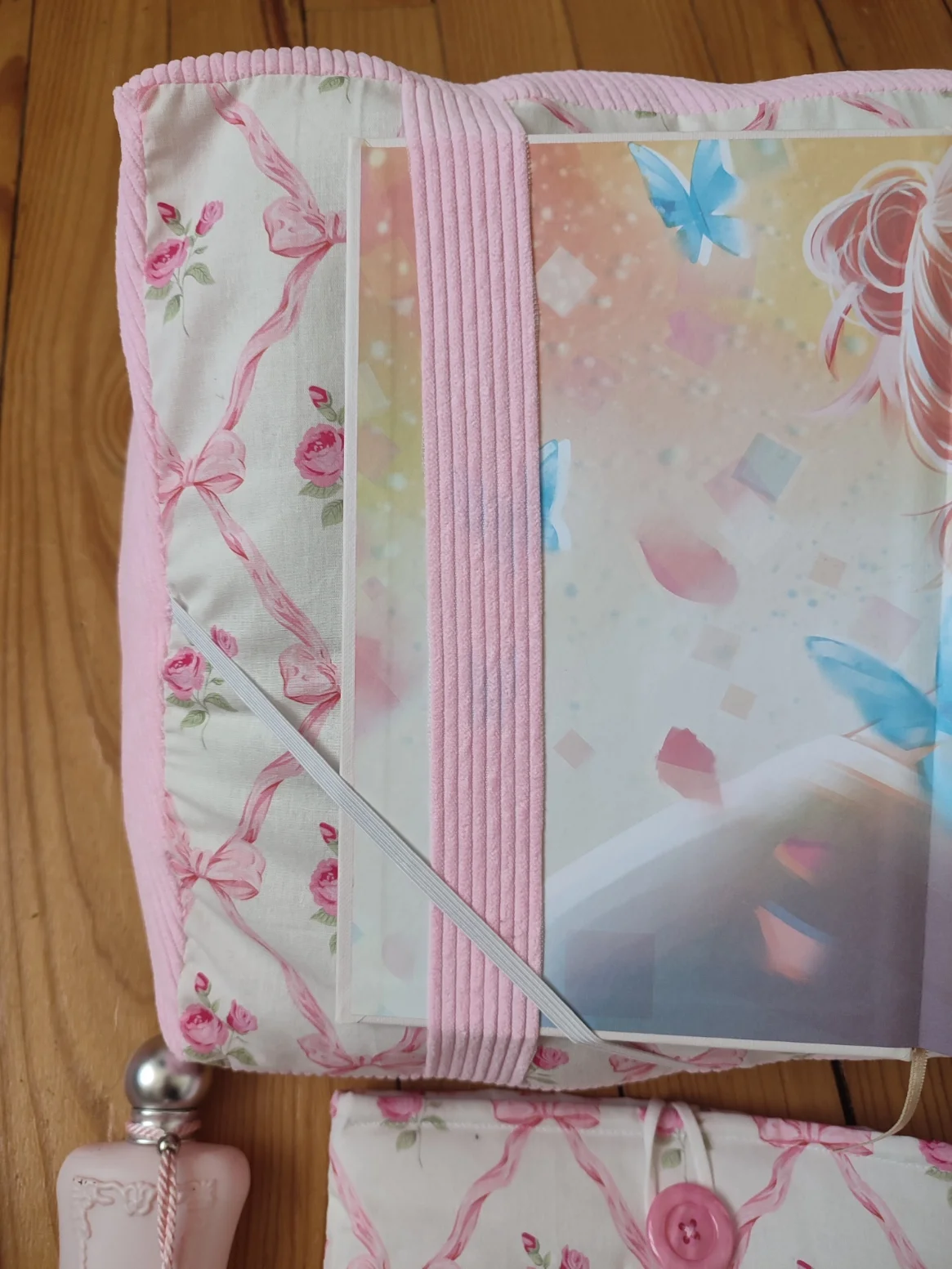 Coussin de lecture ruban rose fait main avec un tissus représentant des noeuds rose et des rose fushia sur fond bland et un tissus côtelé rose vue avec la page de garde d'un livre