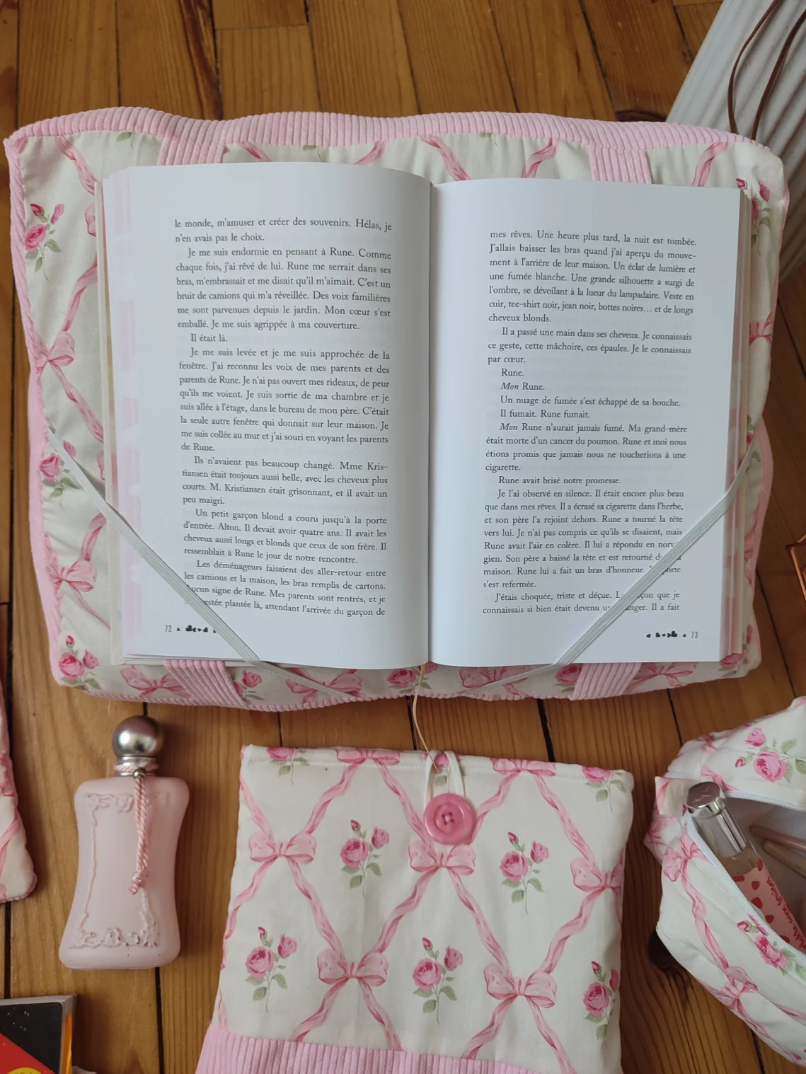 Coussin de lecture ruban rose fait main avec un tissus représentant des noeuds rose et des rose fushia sur fond bland et un tissus côtelé rose avec un livre ouvert