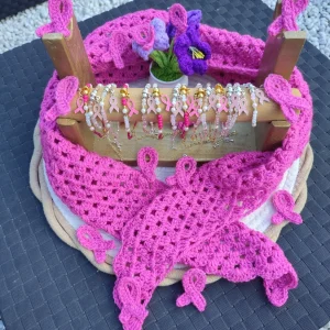 Foulard bandana rose foncé sur un mannequin, badge insigne de la lutte contre le cancer du sein et des bracelets en perle