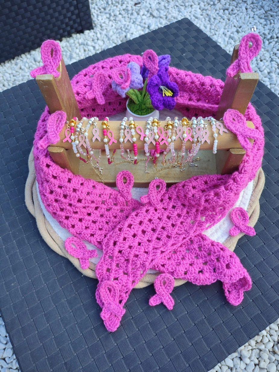 Foulard bandana rose foncé sur un mannequin, badge insigne de la lutte contre le cancer du sein et des bracelets en perle