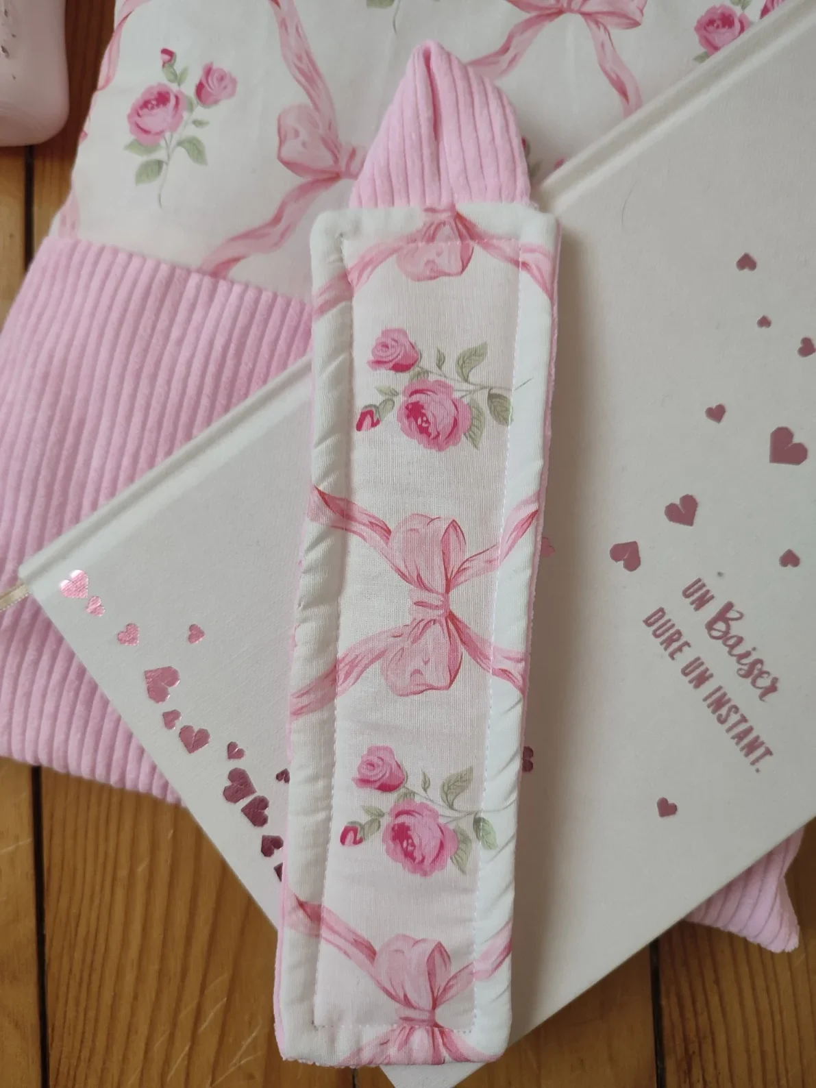 Marque page ruban rose fait main avec un tissus représentant des noeuds rose et des rose fushia sur fond bland et un tissus côtelé rose